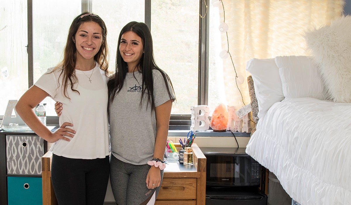 two female students standing together in a dorm room