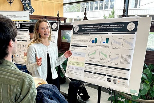 Undergraduate explaining her research project to neuroscience symposium attendee