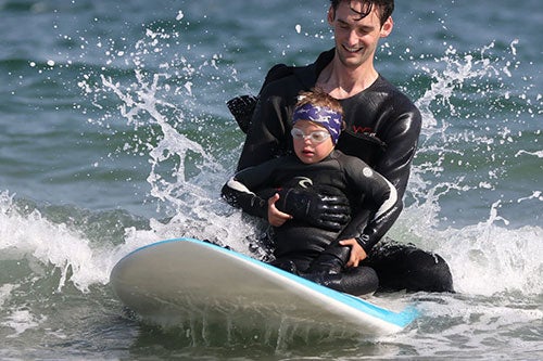 member of URI Surf Therapy Program helping a child with visual impairment